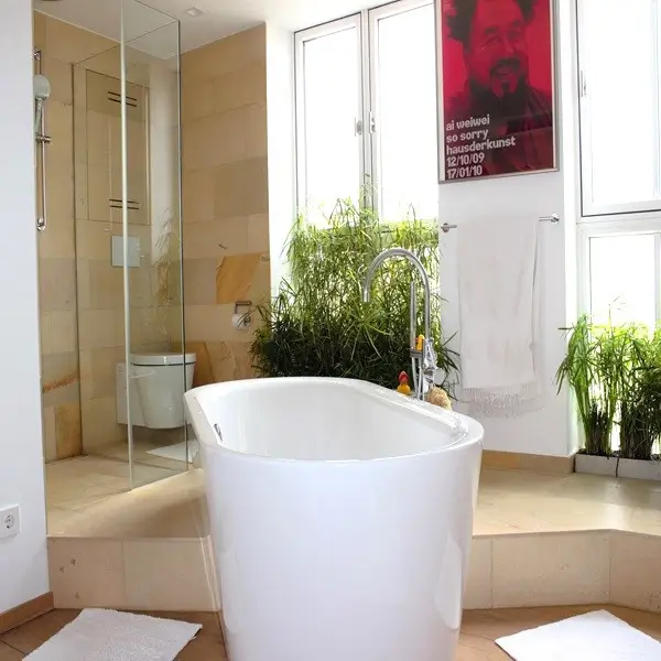 Luxuriöses Badezimmer mit Natursteinfliesen an der Wand und Boden und mit frei stehender Badewanne im Raum